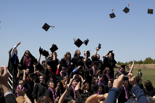 Graduates celebrate commencement by throwing their caps in the air