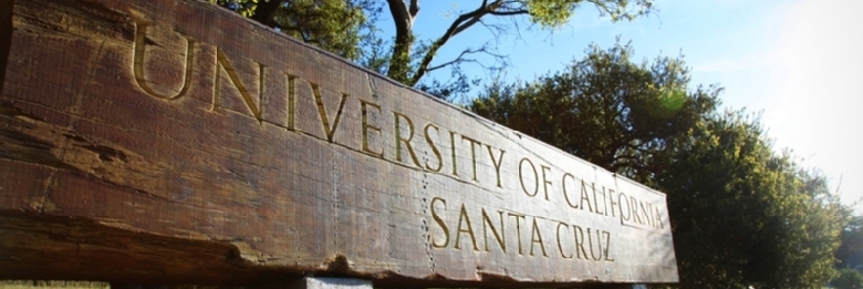Large horizontal piece of redwood tree fashioned into an entry sign at the base of UC Santa Cruz campus